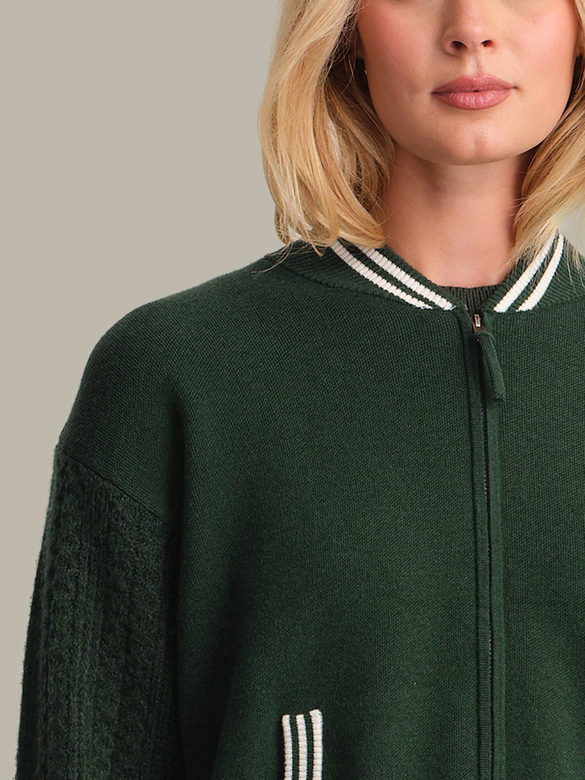 Green jacket with white trim worn by a person, on a neutral background