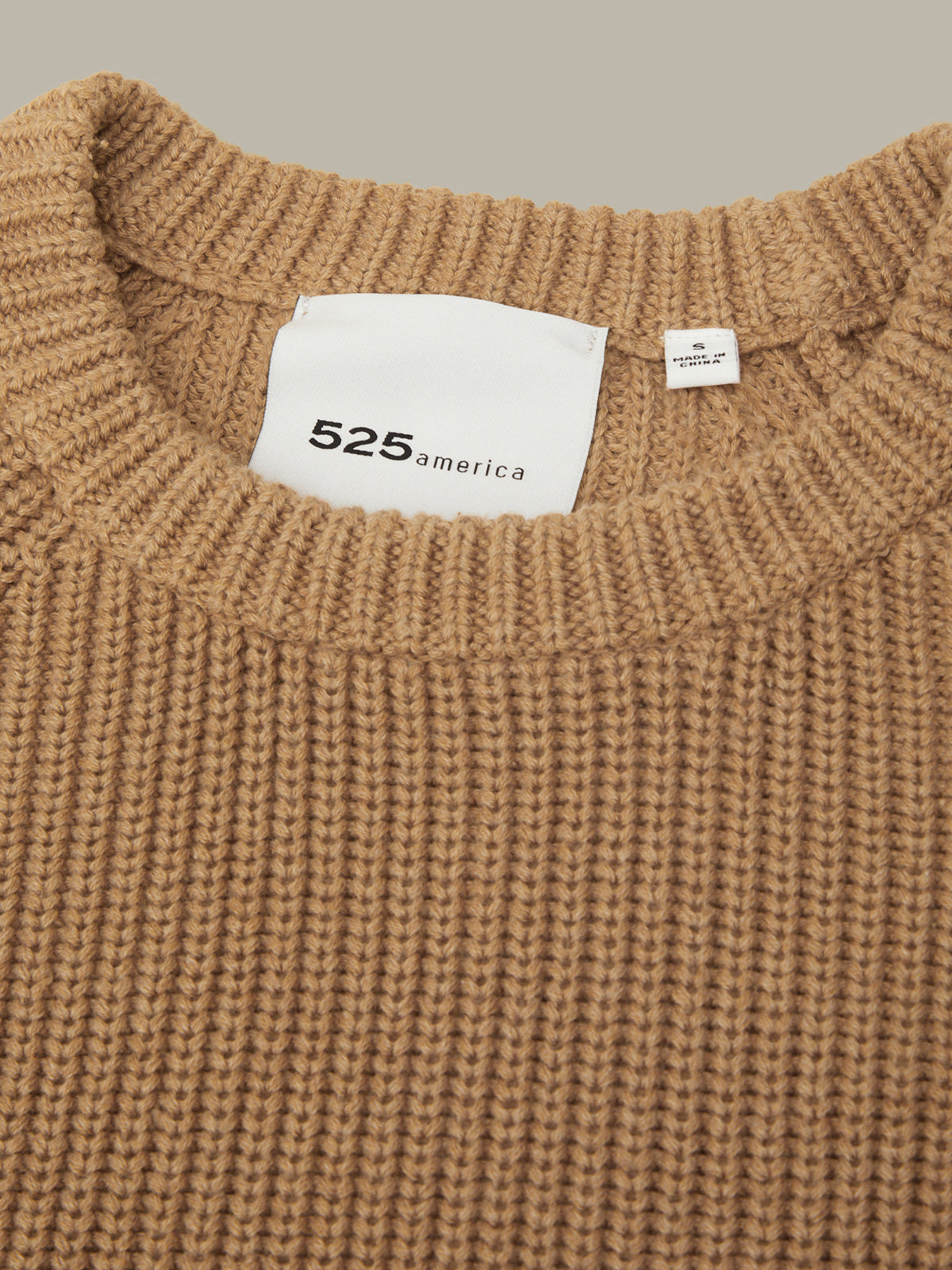 Close-up of a brown knitted sweater with a visible brand label.