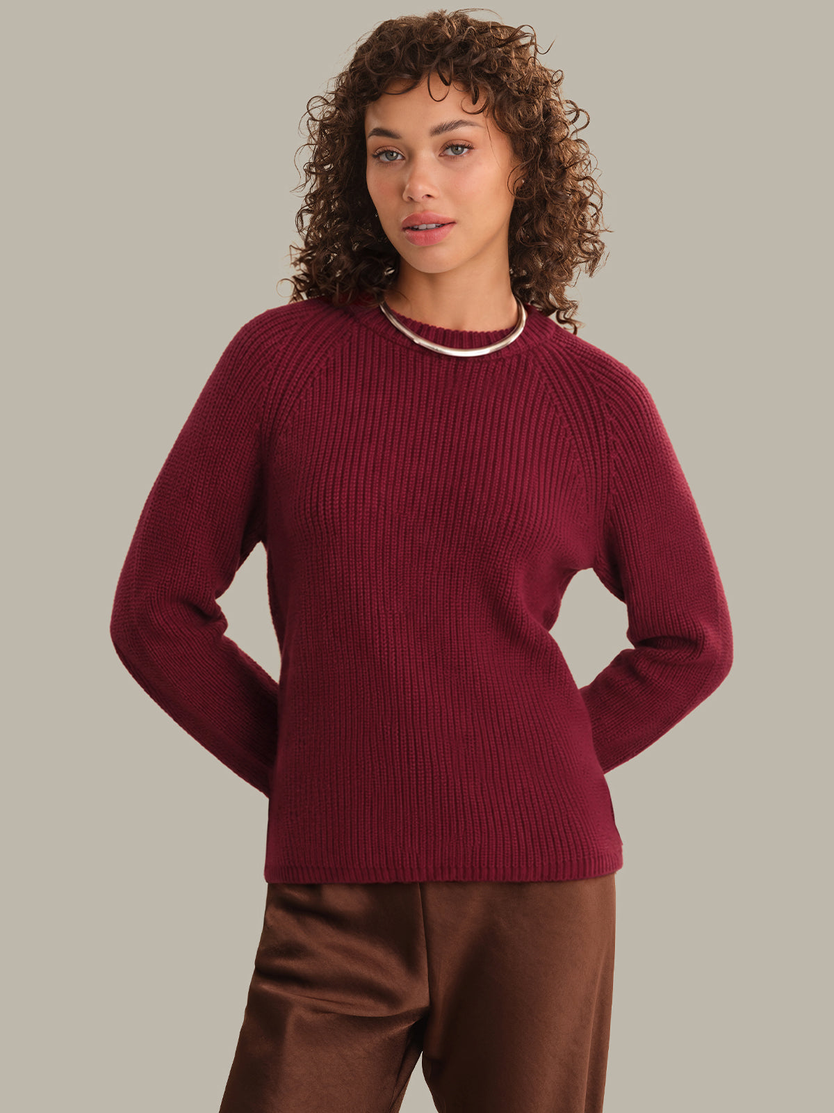 Woman wearing a burgundy sweater against a plain background