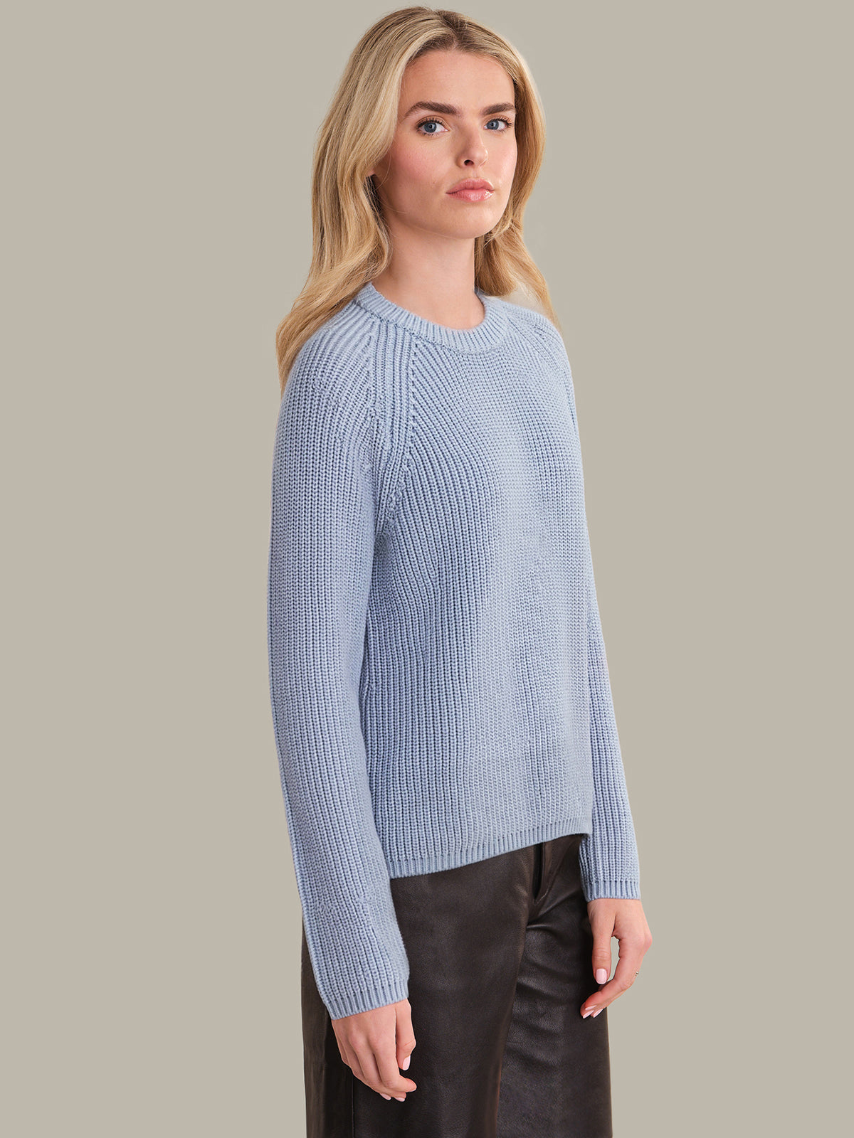 Woman wearing a light blue sweater against a plain background