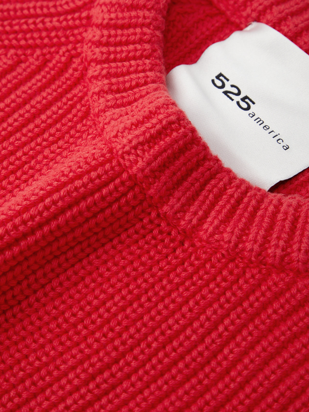 Close-up of a red sweater with a white label displaying '525 america'.