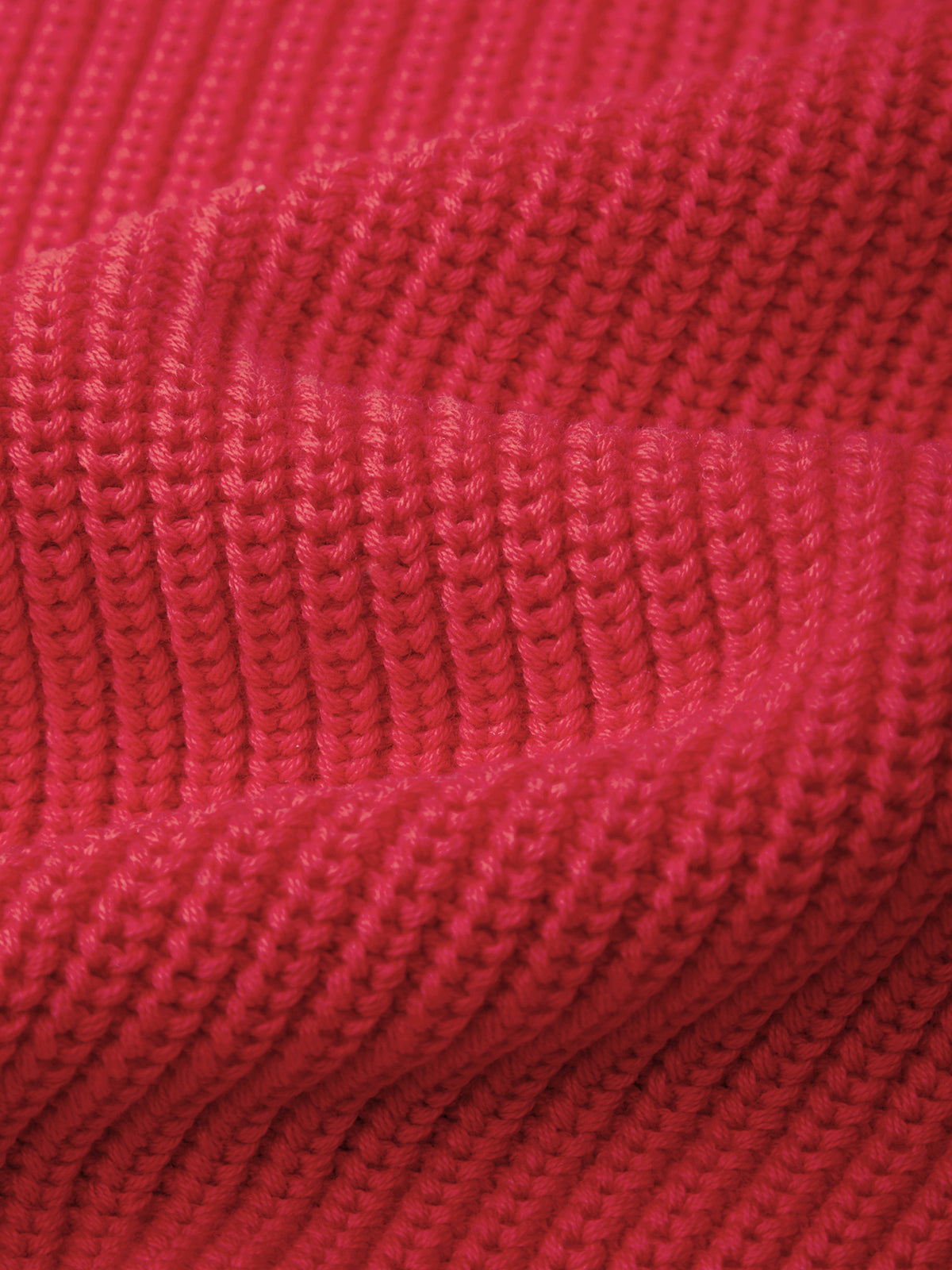 A close-up of a vibrant red ribbed knit fabric, showing the detailed texture of the knit stitches and soft folds.