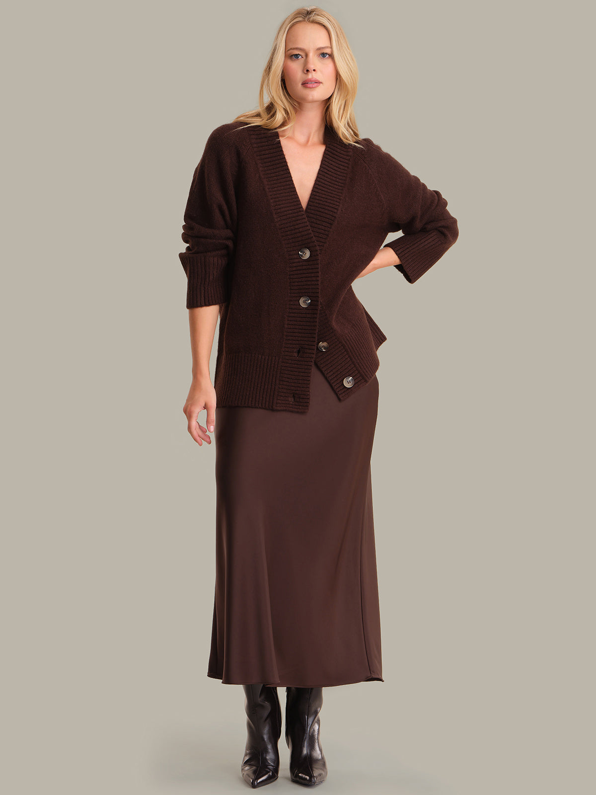 Woman wearing a brown cardigan and skirt set on a gray background