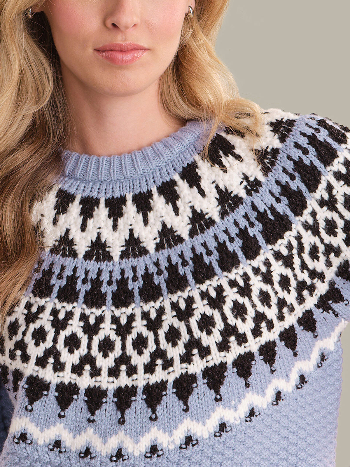 Close-up of a person wearing a patterned sweater with blue, black, and white colors.