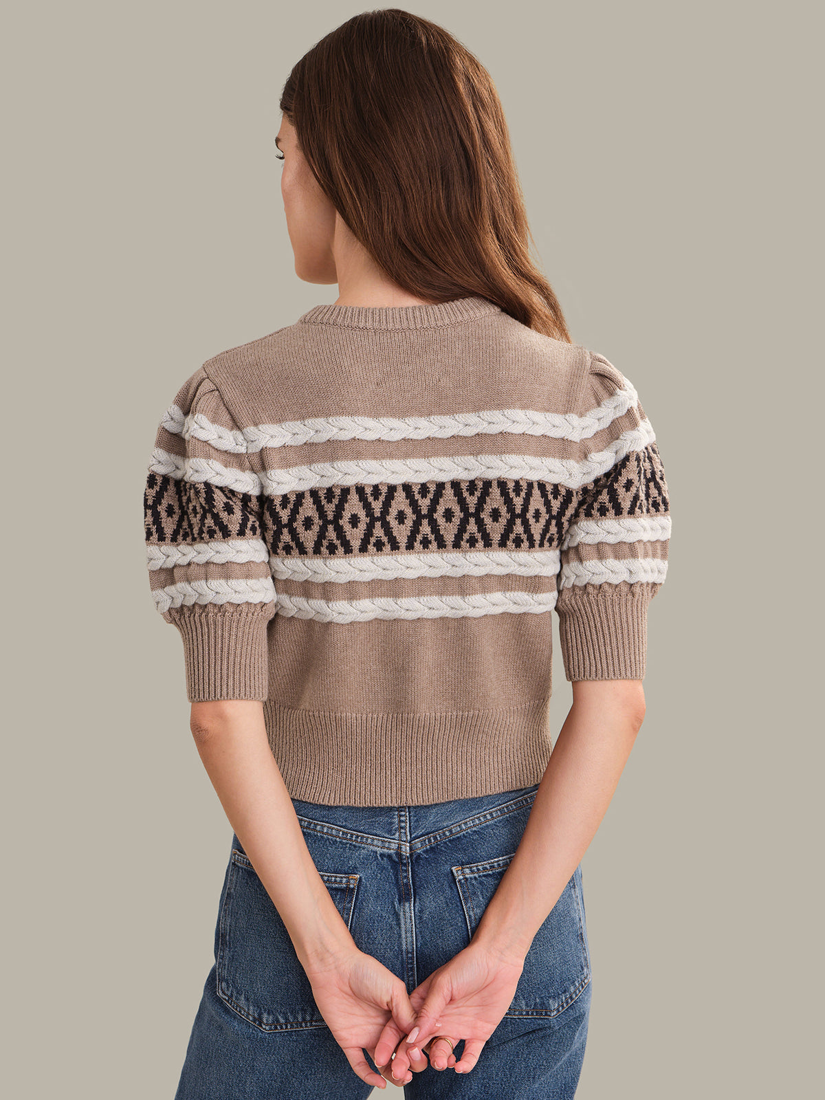 Person wearing a patterned cardigan with a neutral background