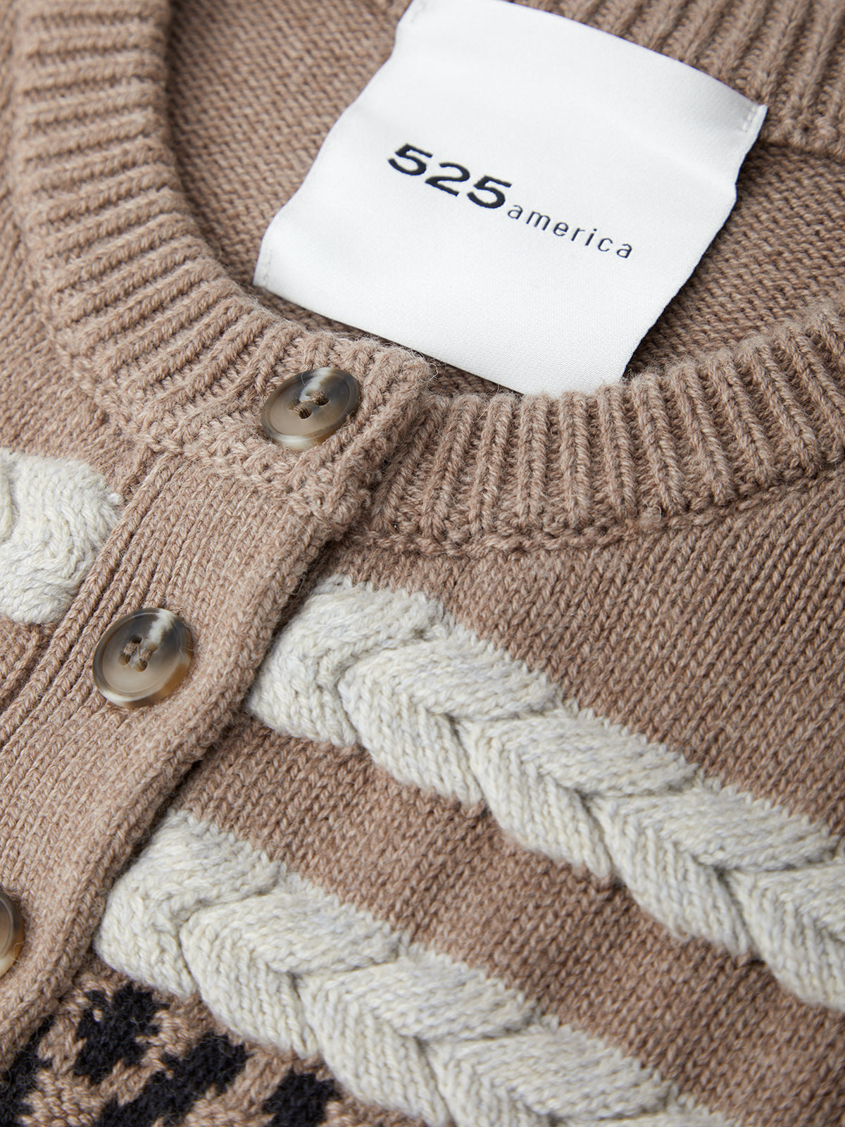 Close-up of a brown knitted sweater with braided pattern and '525 america' label.