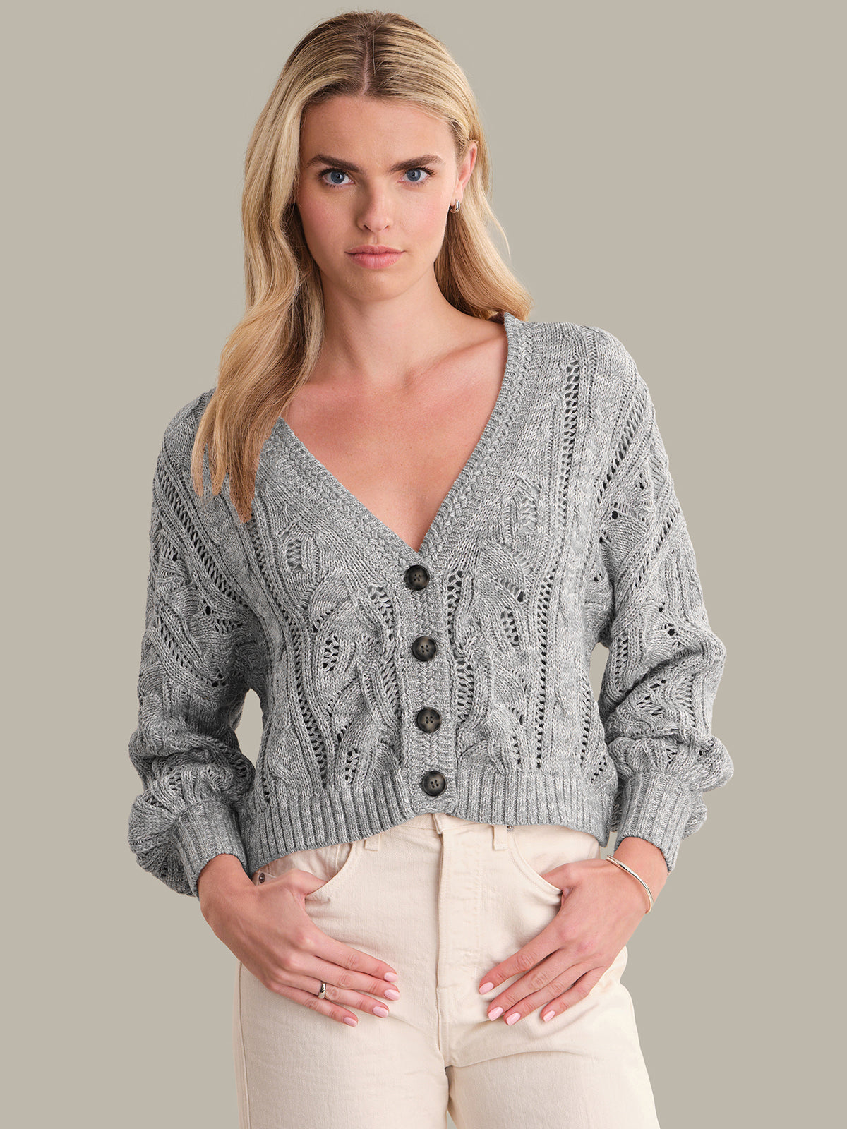 Woman wearing a gray knitted cardigan against a plain background