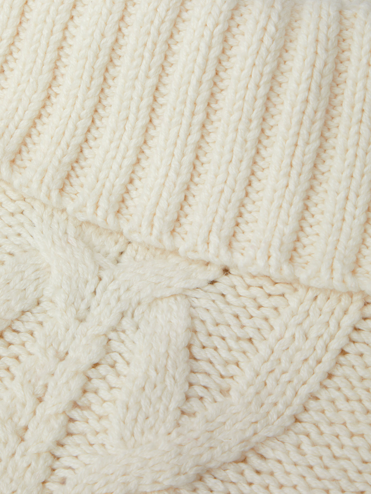 Close-up of a textured beige fabric with a cable knit pattern