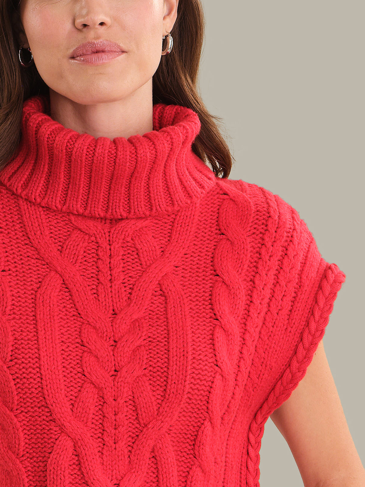 Red knitted sleeveless sweater worn by a person on a gray background