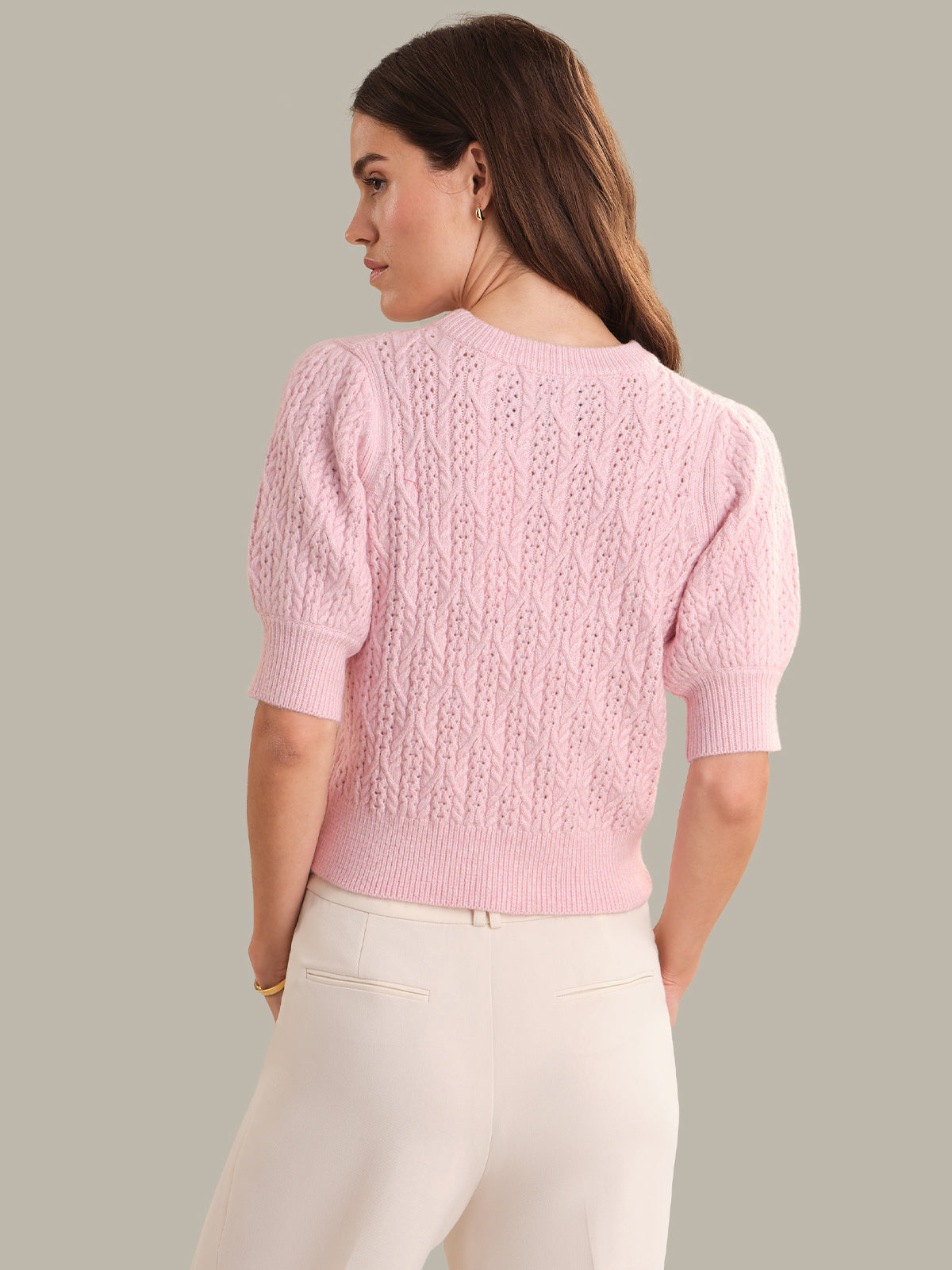 Woman wearing a pink knitted sweater against a plain background