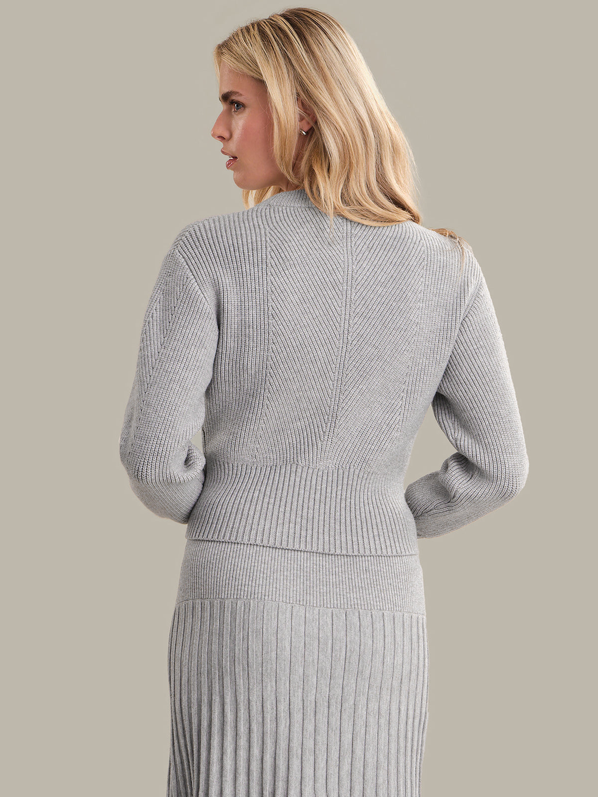 Woman wearing a gray ribbed knit outfit on a plain background