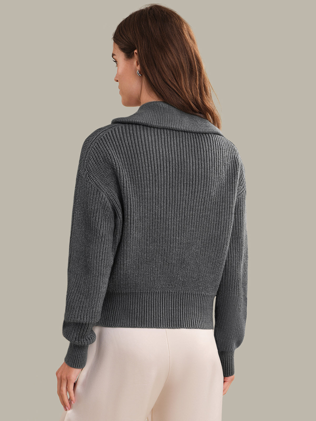 Woman wearing a gray knitted cardigan against a plain background