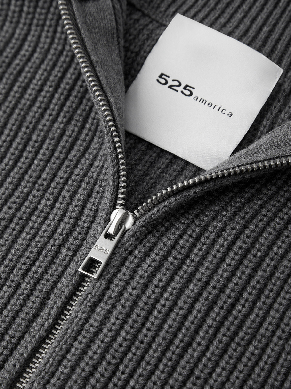 Close-up of a gray zippered garment with a '525 America' label.