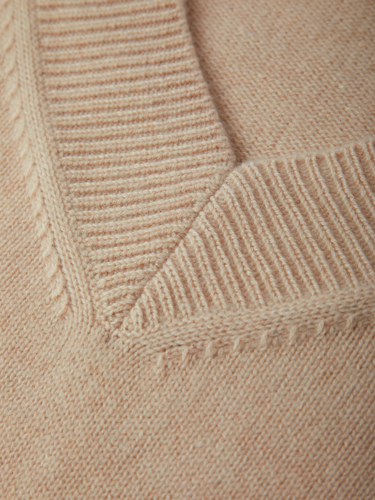 Close-up of a beige knitted fabric with a brand label.