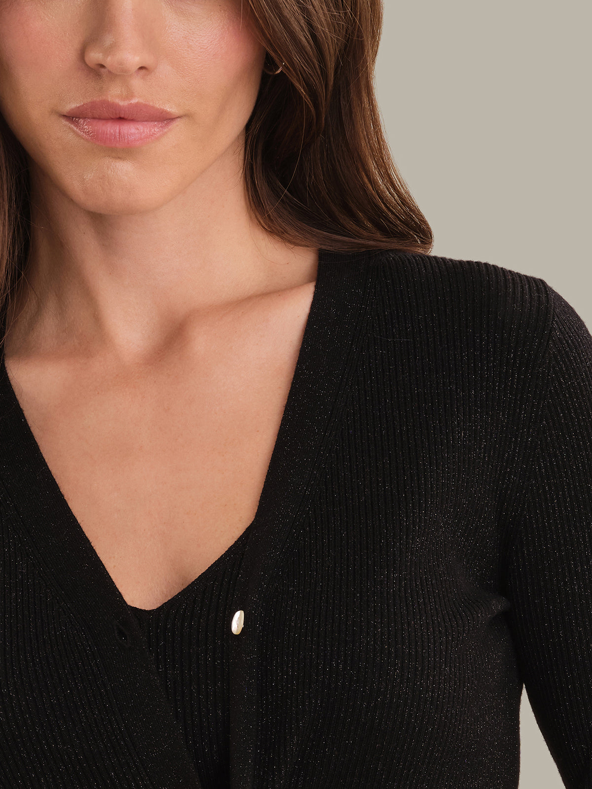 Close-up of a person wearing a black ribbed sweater with a neutral background