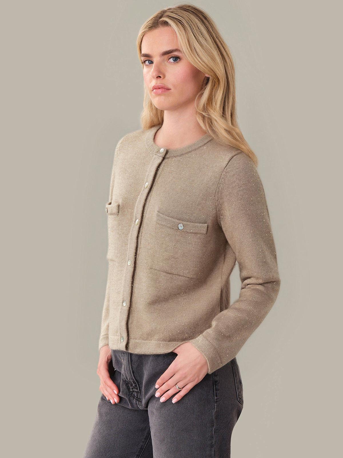 Woman wearing a beige cardigan against a plain background