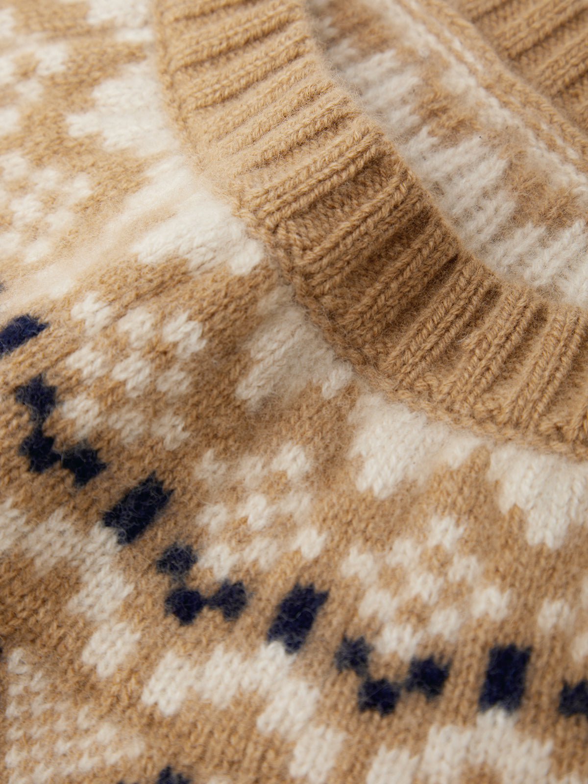 Close-up of a knitted sweater with a pattern featuring brown, beige, and navy colors.