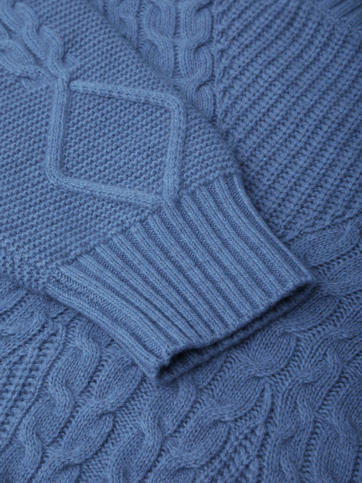 Close-up of a blue knitted sweater with cable pattern