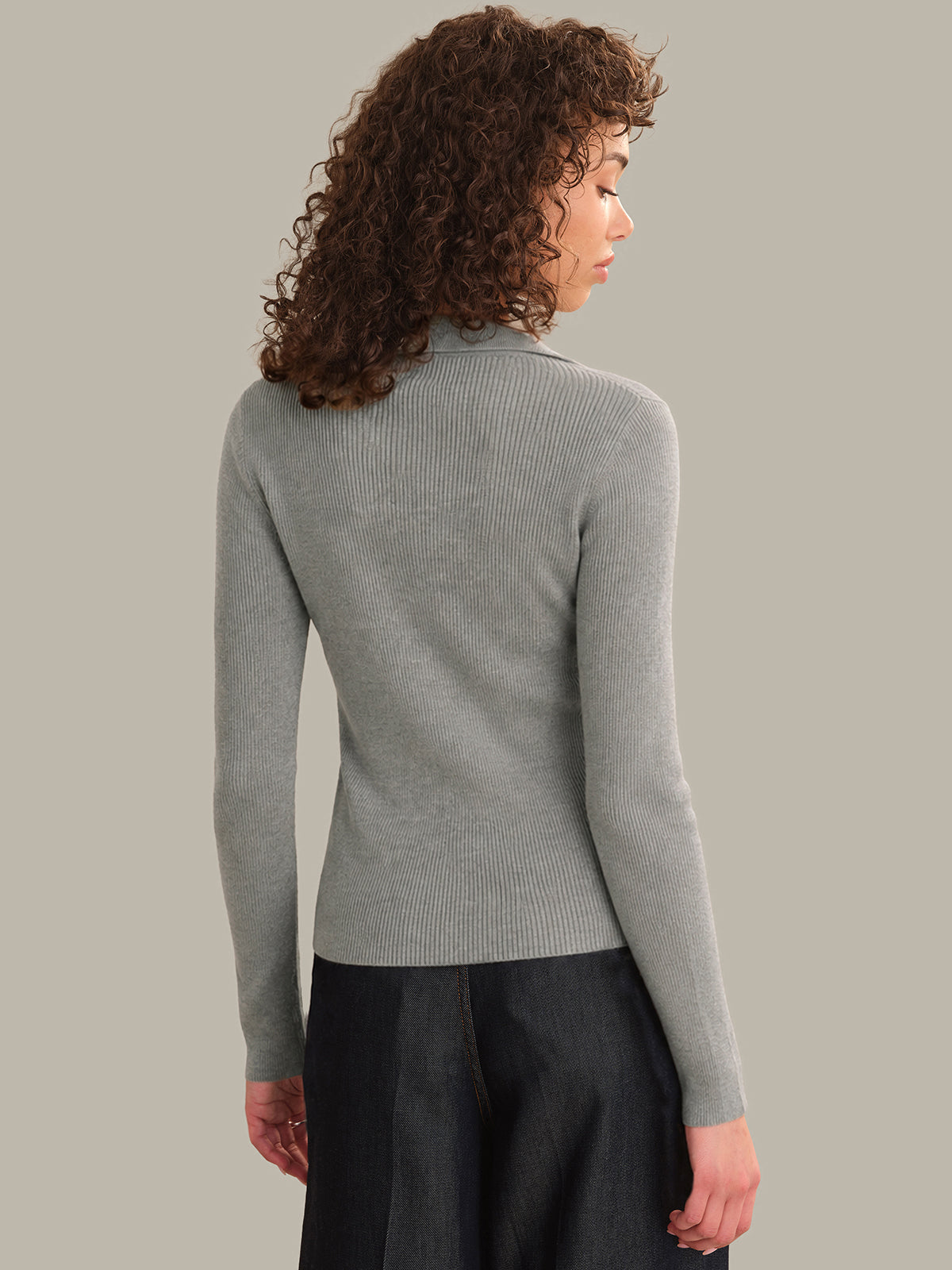 Woman wearing a gray sweater against a plain background