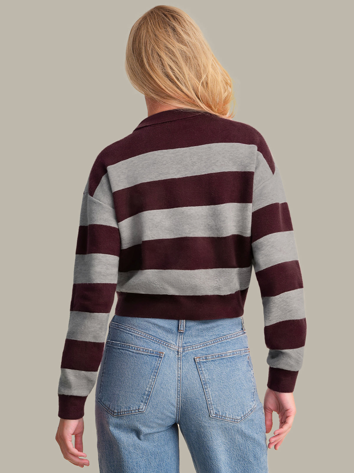 Person wearing a striped sweater and jeans against a plain background
