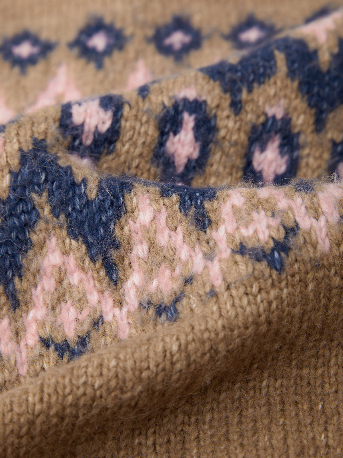 Close-up of a knitted fabric with a pattern featuring brown, pink, and blue colors.