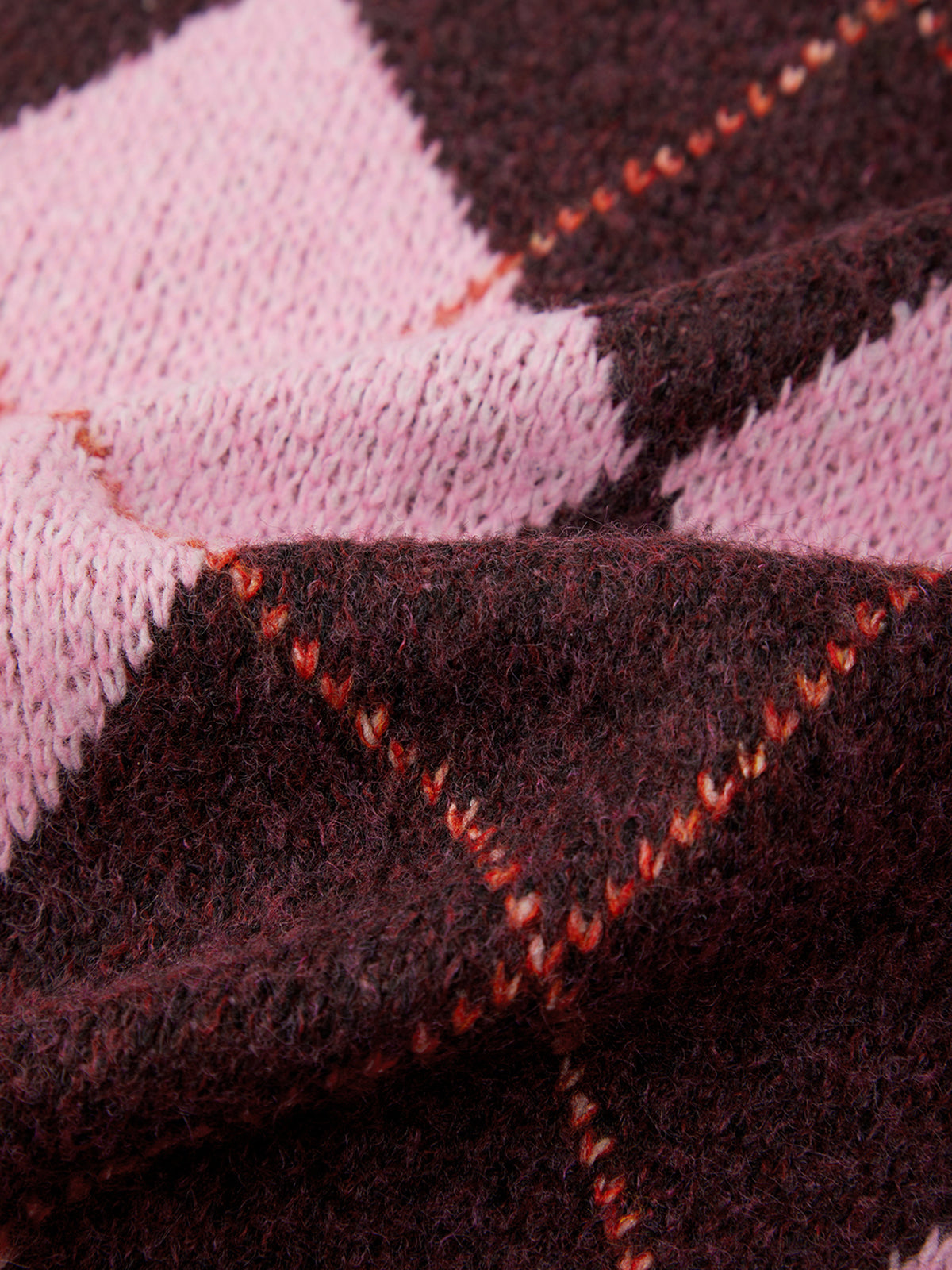 Close-up of a fabric with pink and black checkered pattern and red stitching.