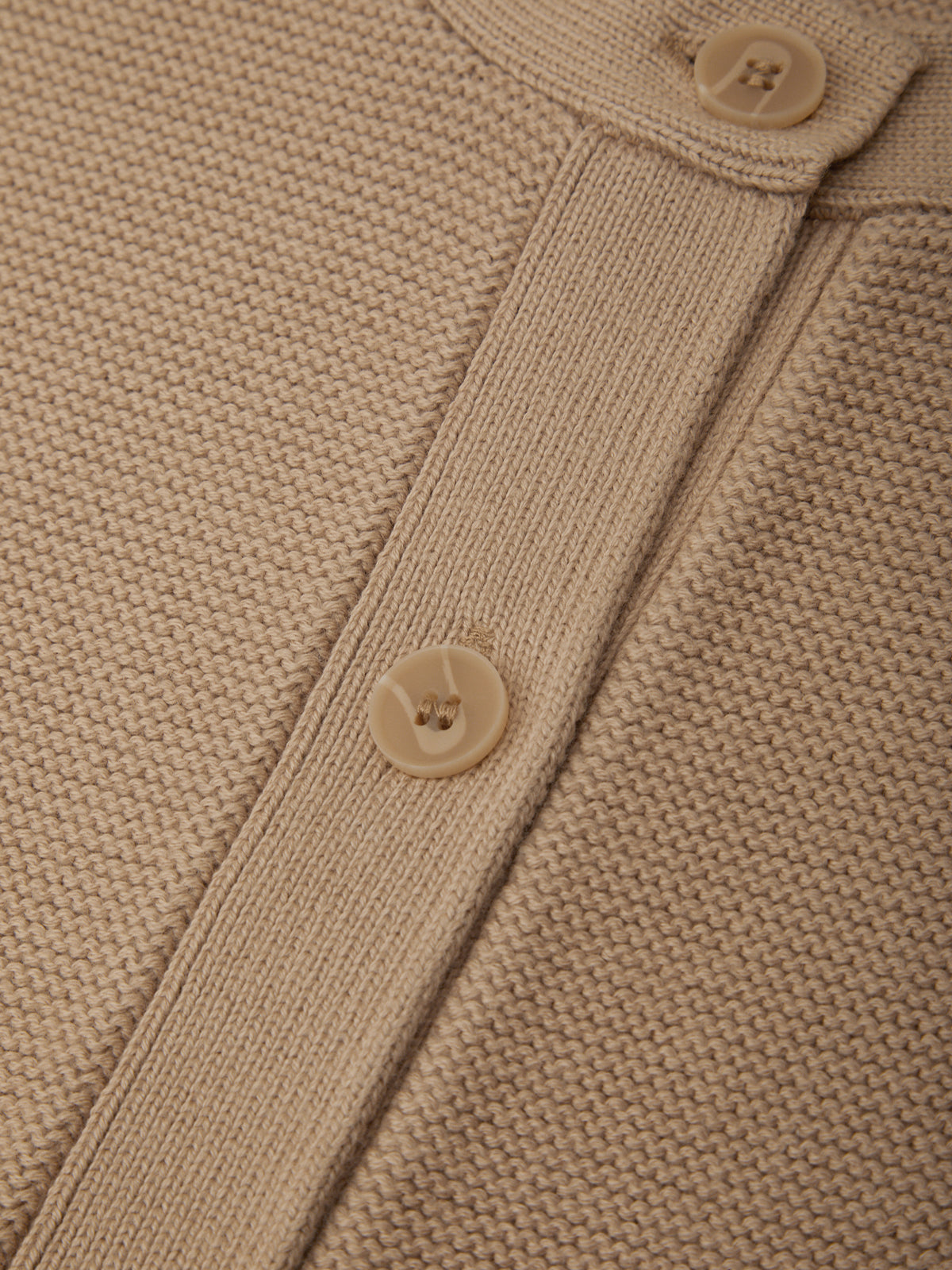 Close-up of a beige knitted cardigan with button details