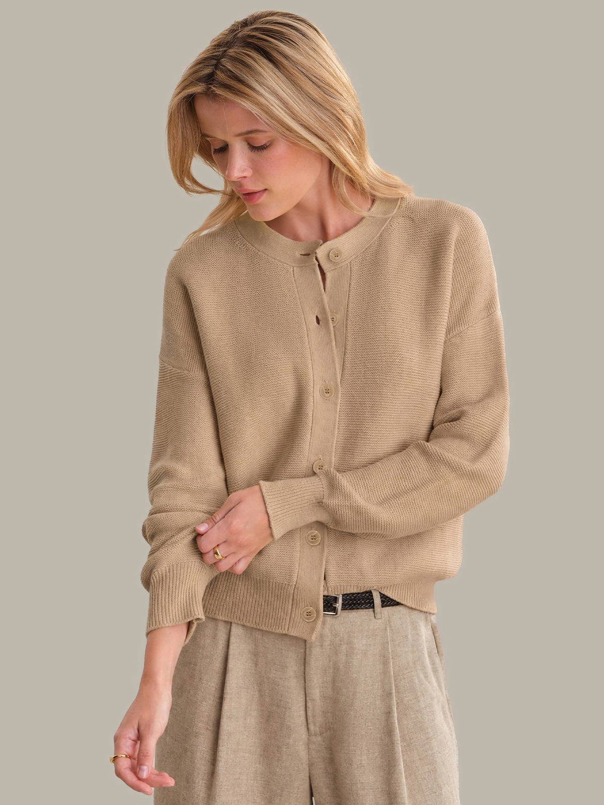 Woman wearing a beige cardigan against a plain background