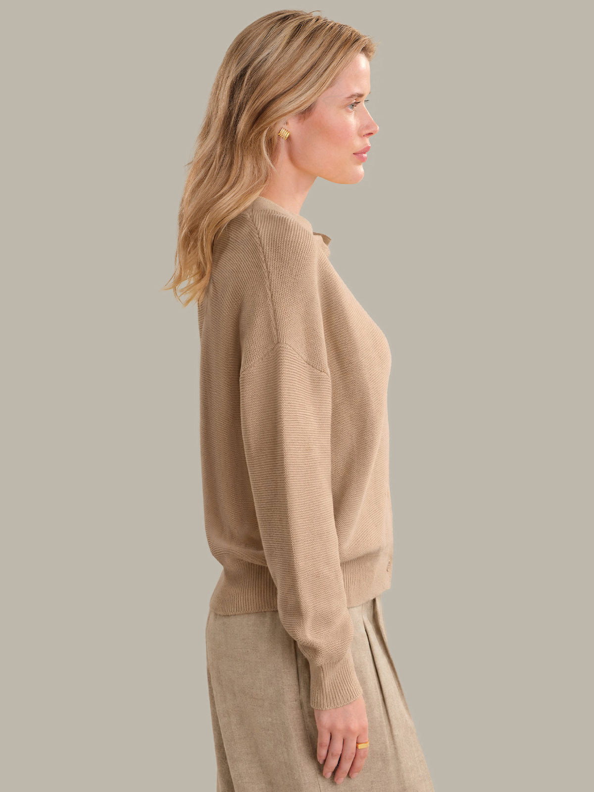 Woman wearing a beige cardigan and skirt set against a plain background