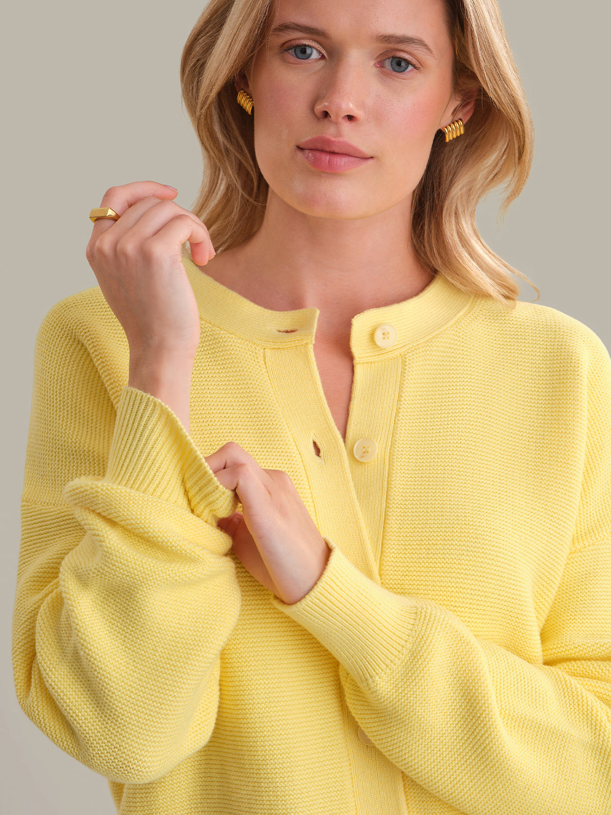 Woman wearing a yellow cardigan against a neutral background