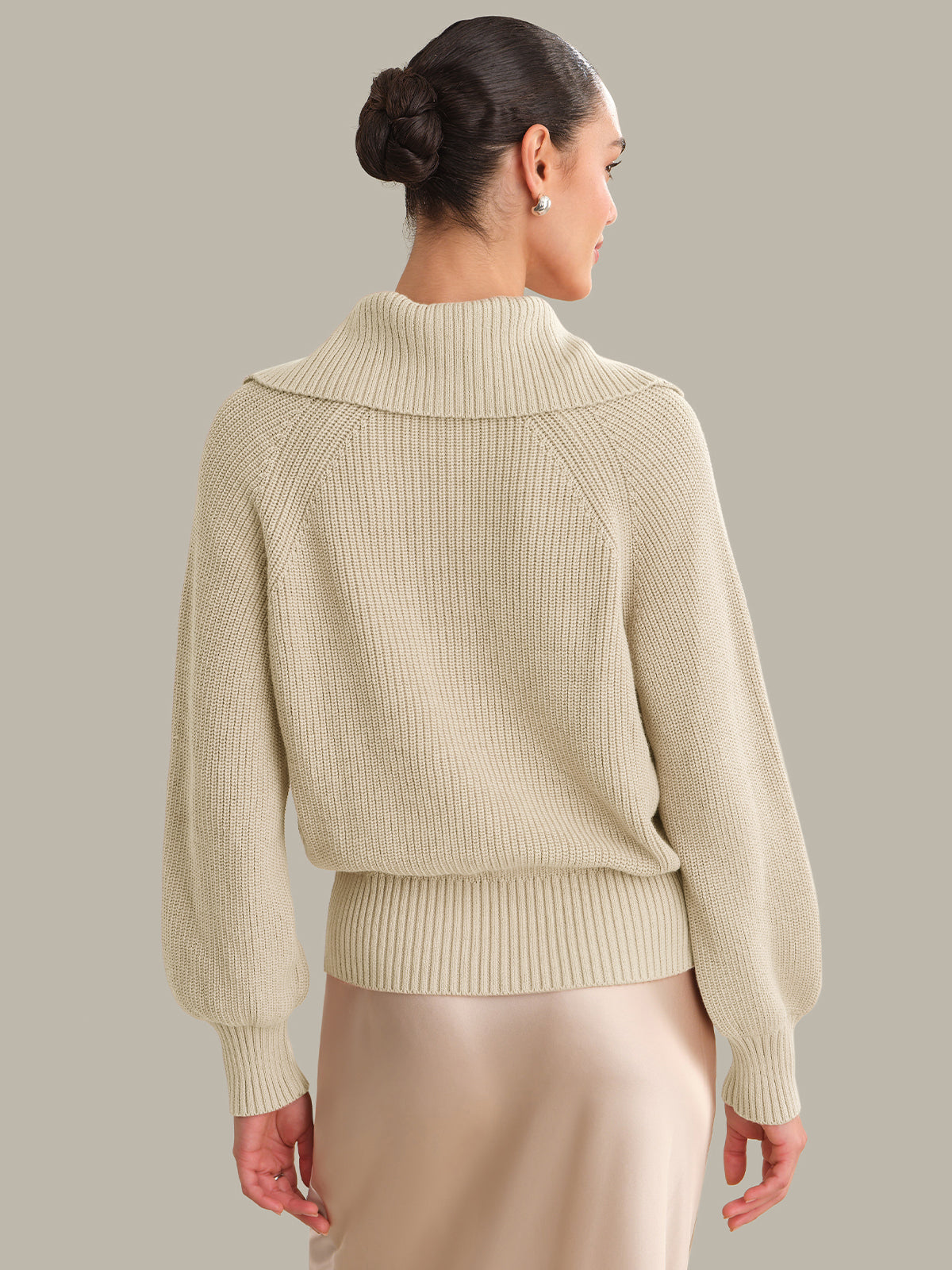 Woman wearing a beige sweater against a neutral background