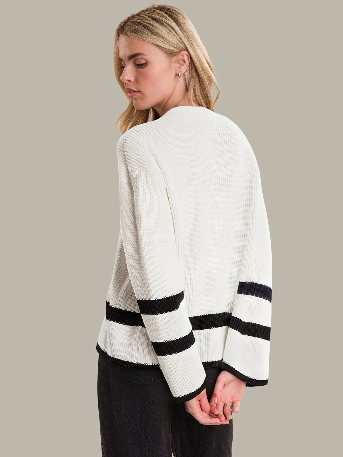 Woman wearing a white sweater with black stripes on a plain background