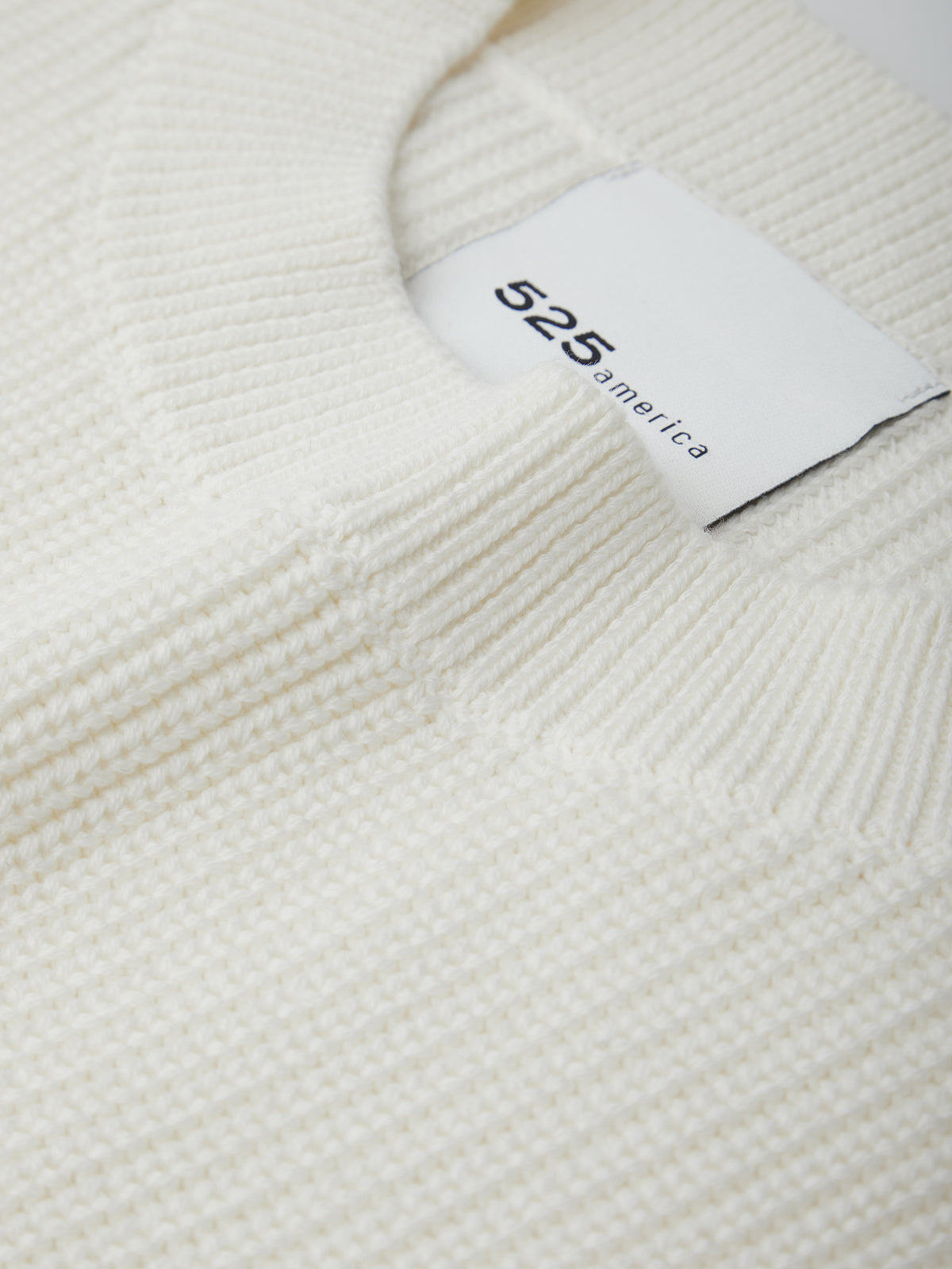 Close-up of a white sweater with a label on a white background