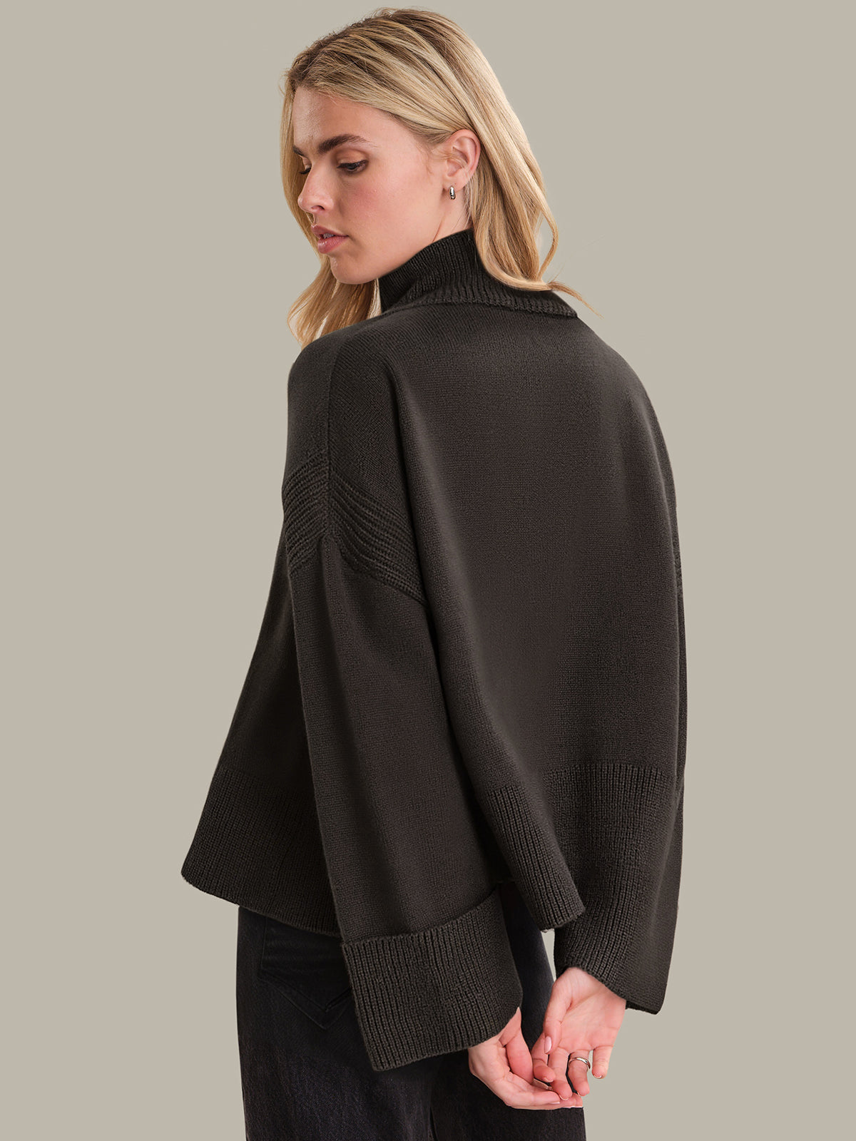 Woman wearing a brown sweater against a plain background