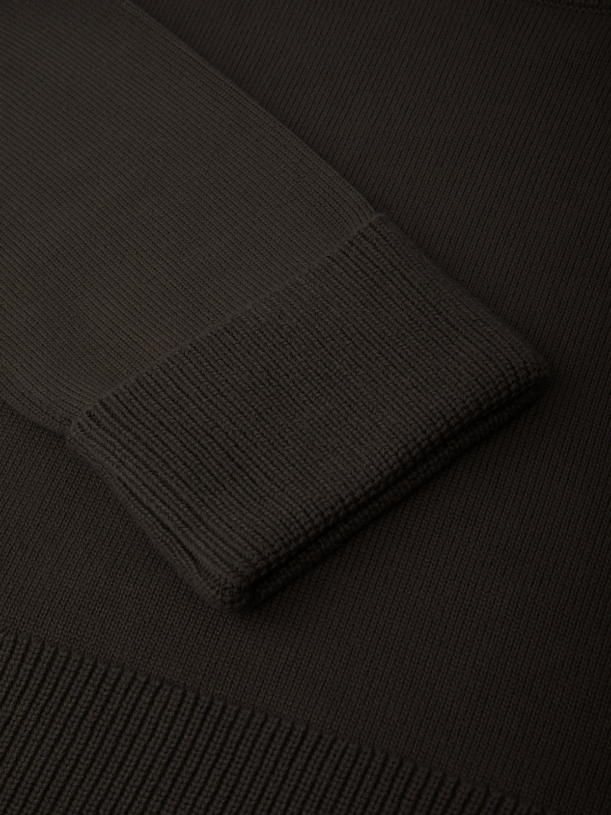 Close-up of a brown knitted sweater with a focus on the texture and pattern.