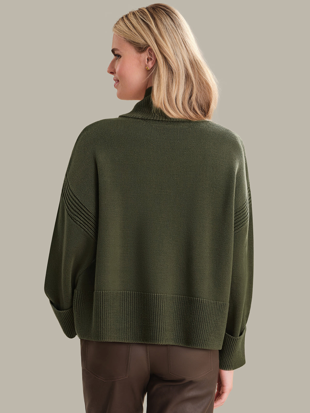 Person wearing a green sweater on a beige background