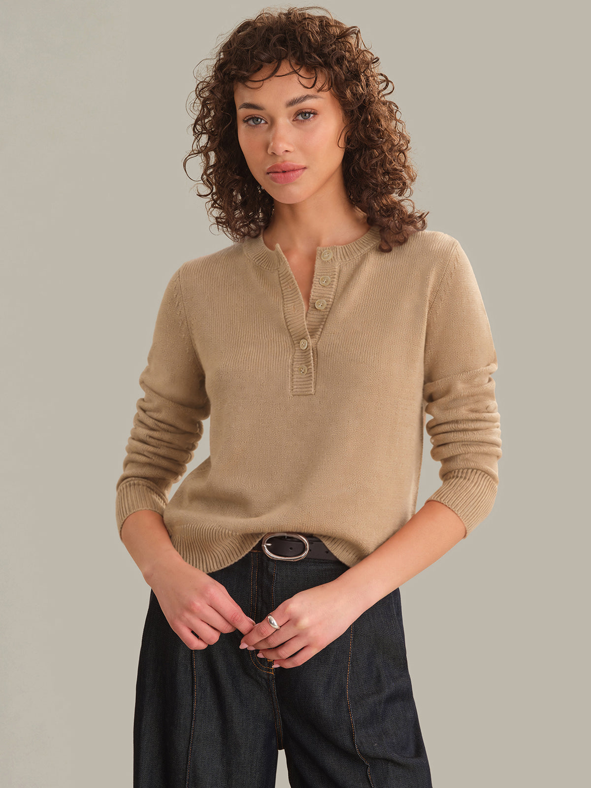 Woman wearing a beige sweater against a plain background