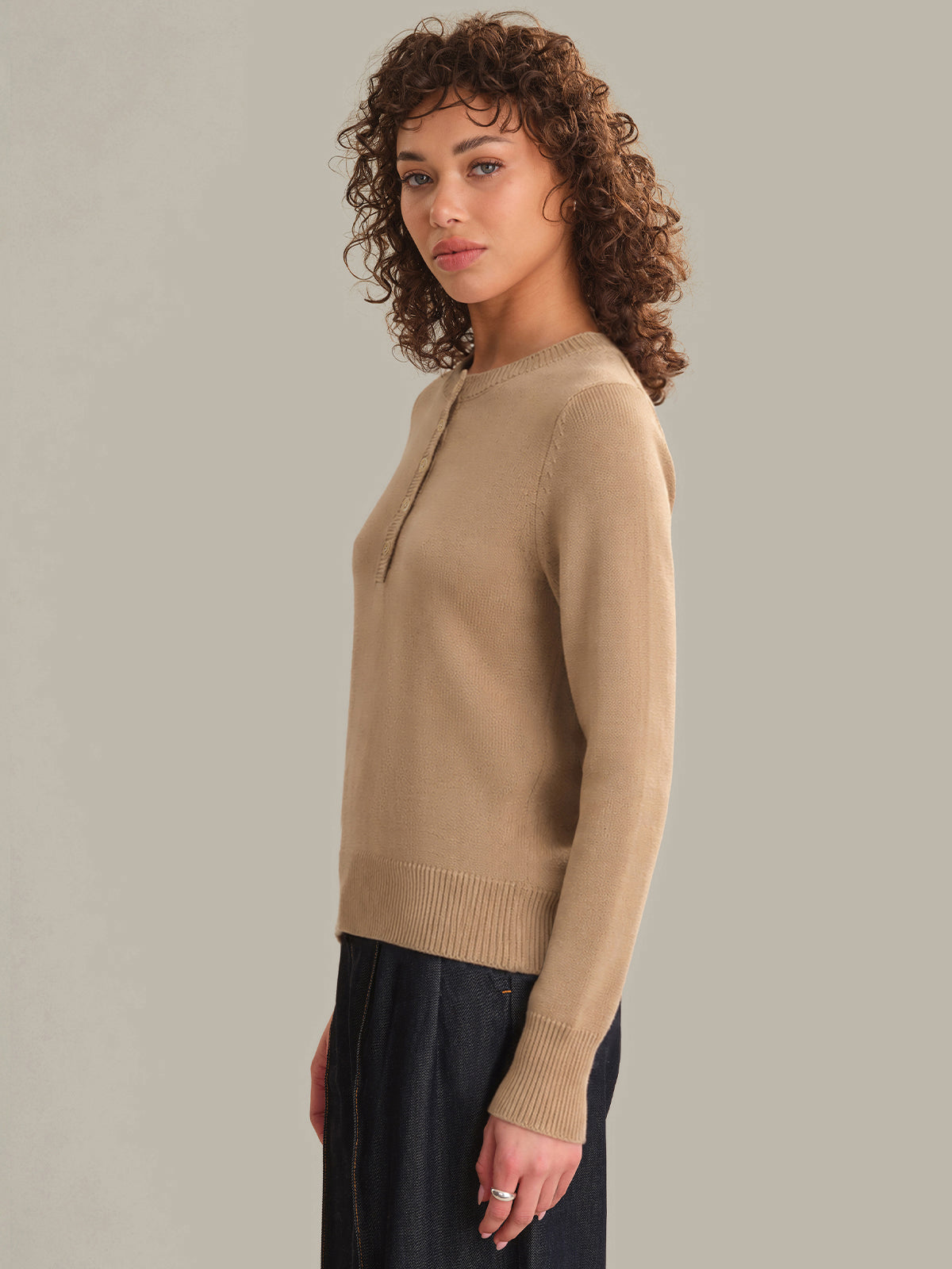 Woman wearing a beige sweater against a plain background