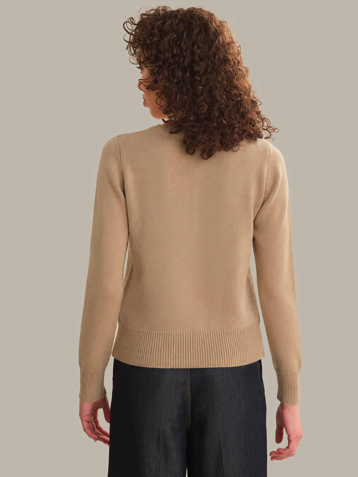 Person wearing a beige sweater against a neutral background