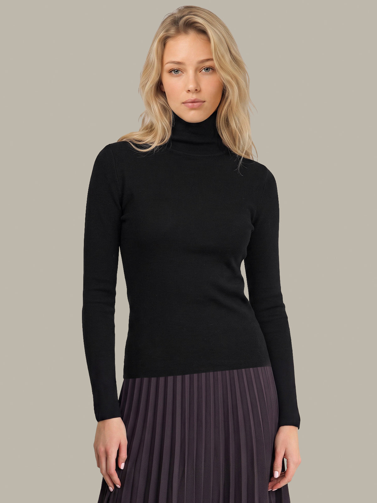A blonde woman wearing a black long-sleeve turtleneck sweater and a pleated dark purple skirt, standing against a solid light gray background.