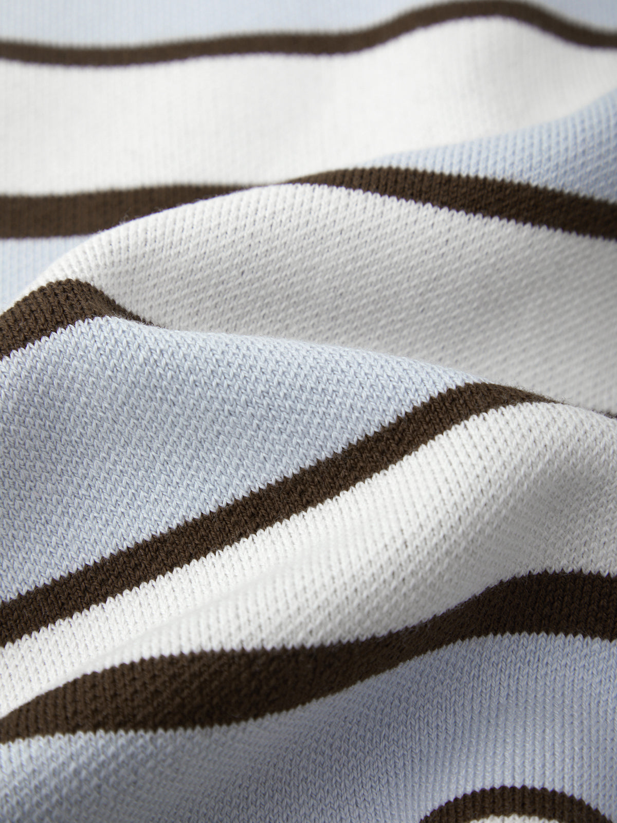 Close-up of a fabric with brown and white stripes on a light blue background