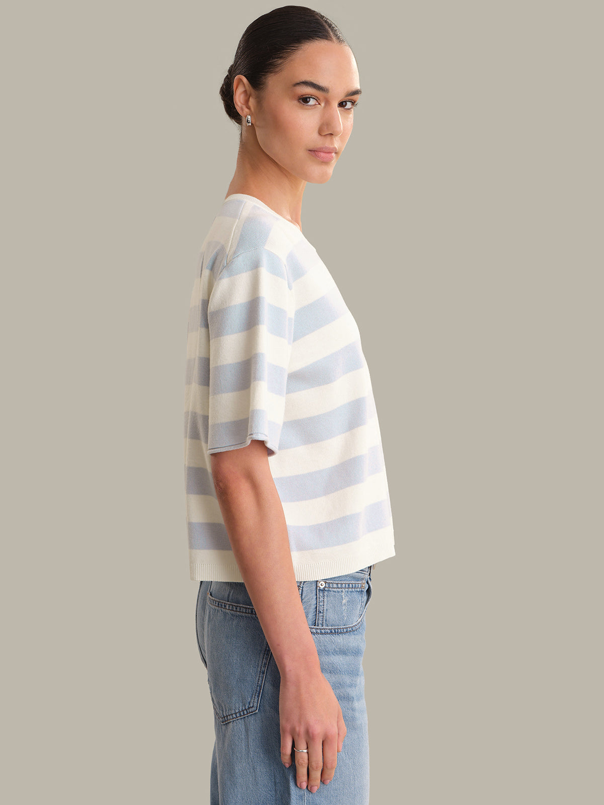 Person wearing a striped shirt and jeans against a plain background