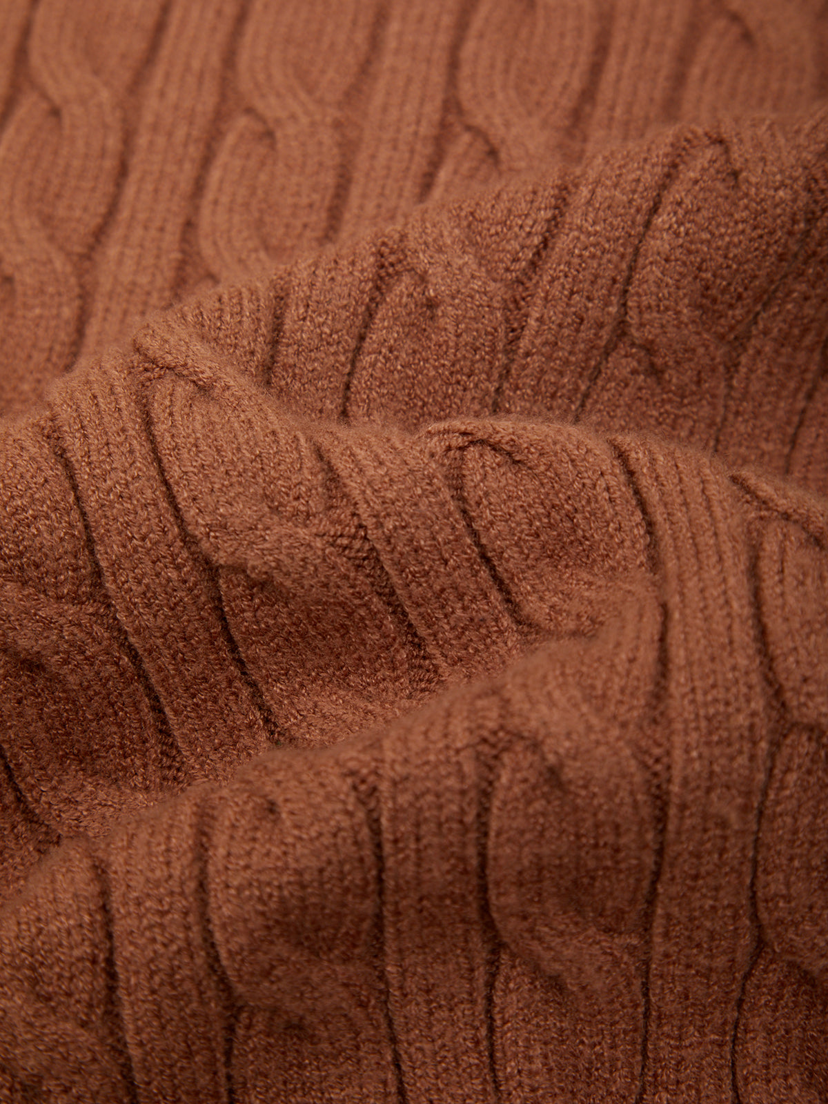 Close-up of a brown cable-knit fabric texture with a ribbed pattern.