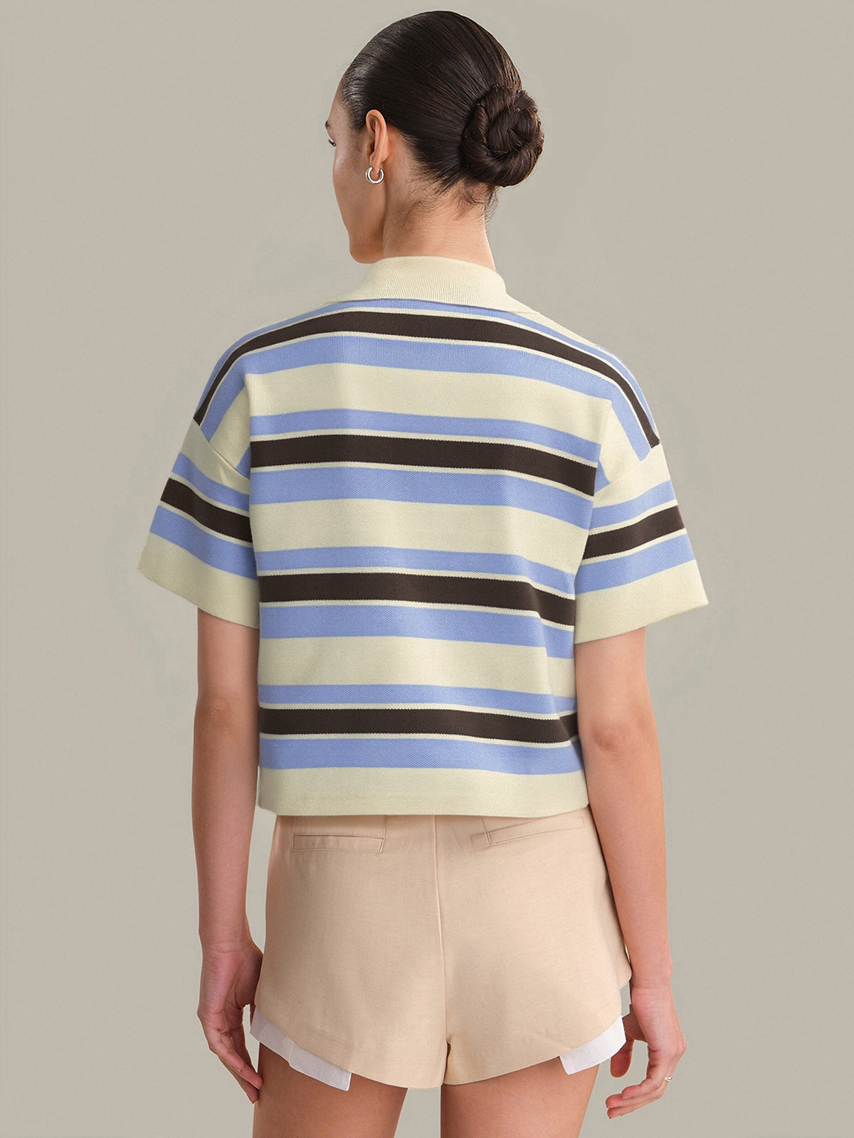 Person wearing a striped shirt and shorts on a plain background