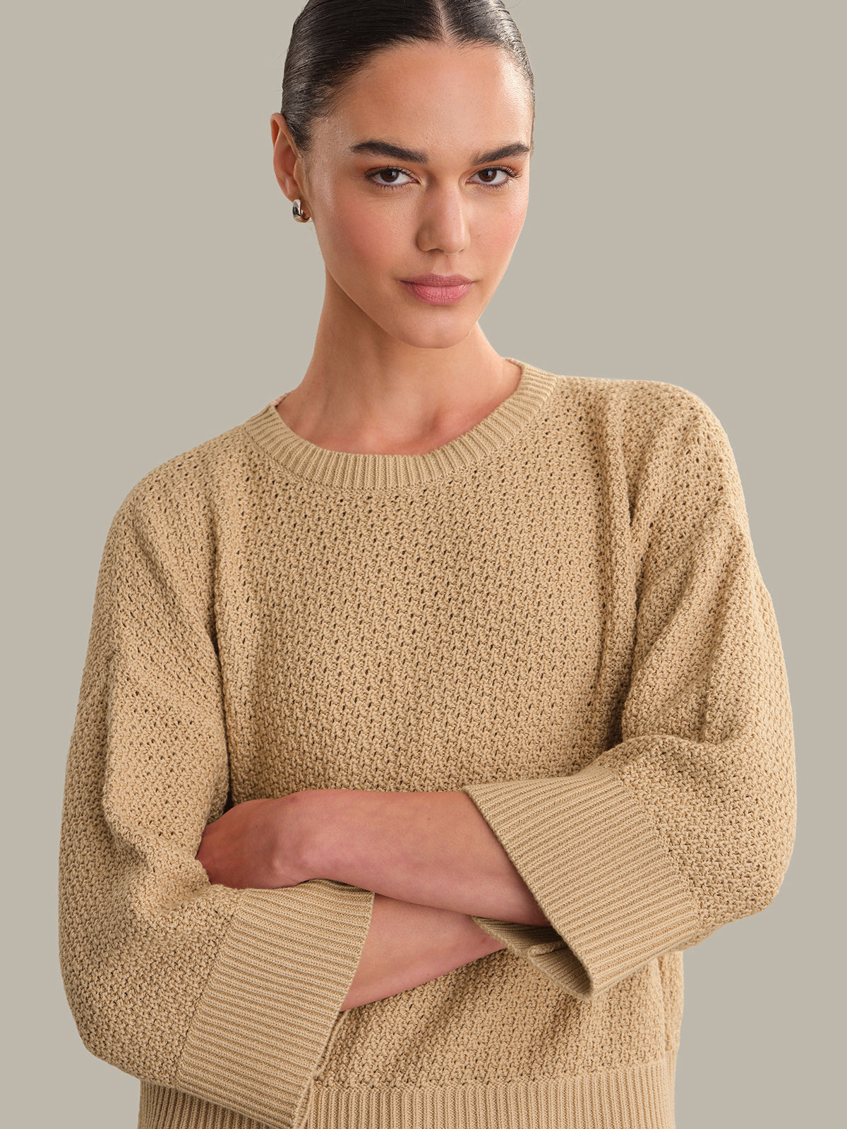 Woman wearing a beige sweater against a plain background