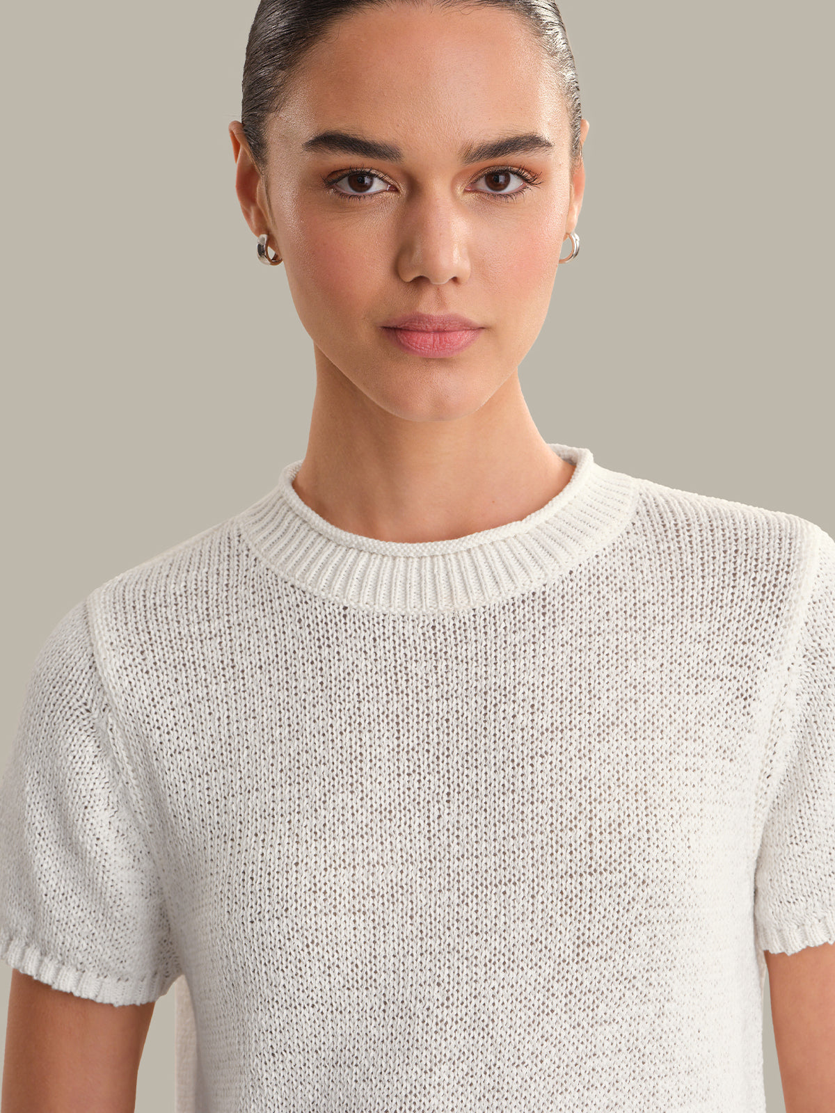 Woman wearing a light gray knit sweater against a neutral background
