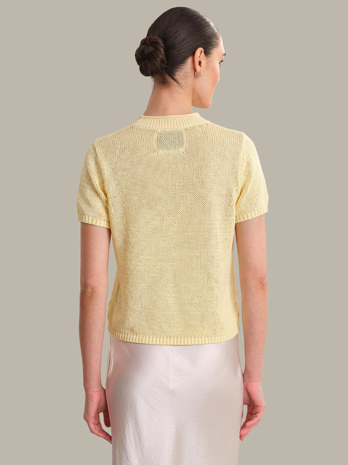 Woman wearing a yellow knit cardigan against a plain background