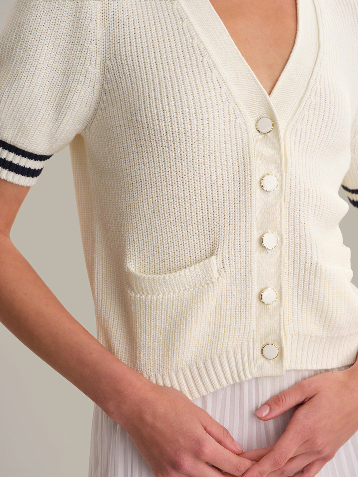 White cardigan with short sleeves and buttons on a neutral background