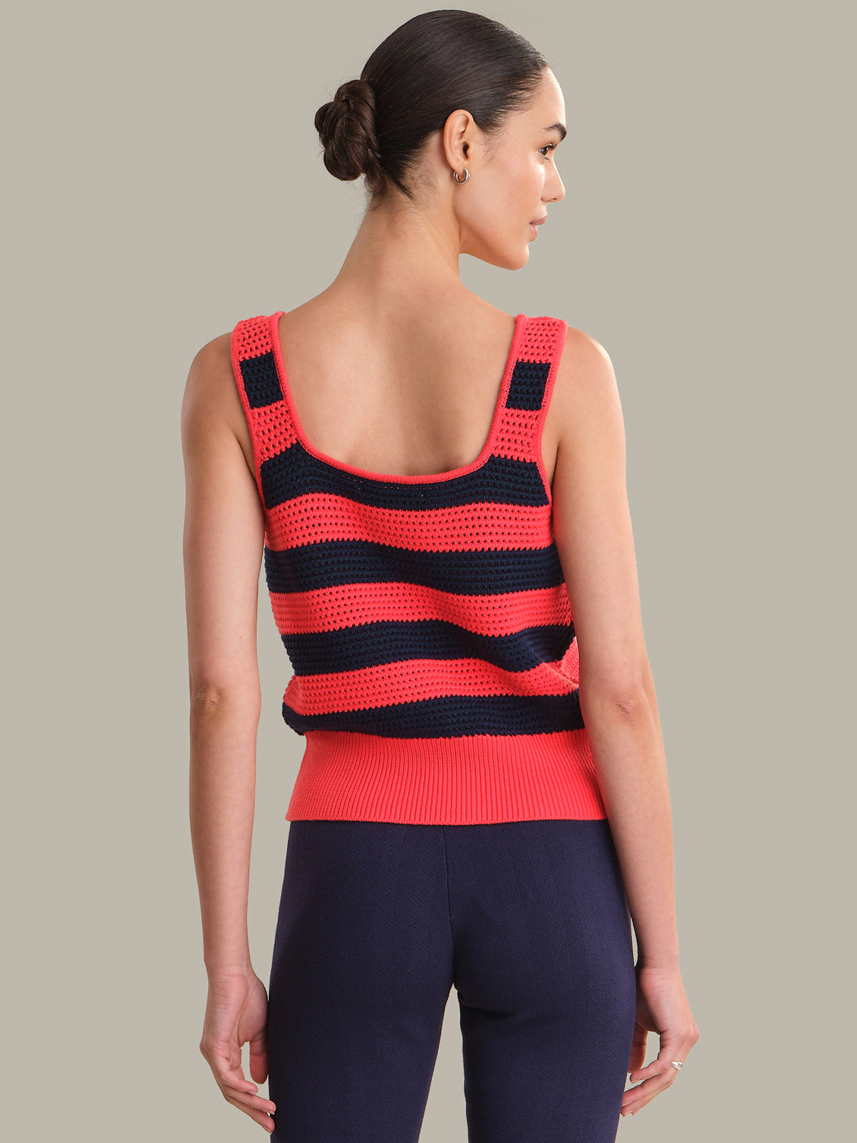 Woman wearing a red and black striped sleeveless top against a neutral background