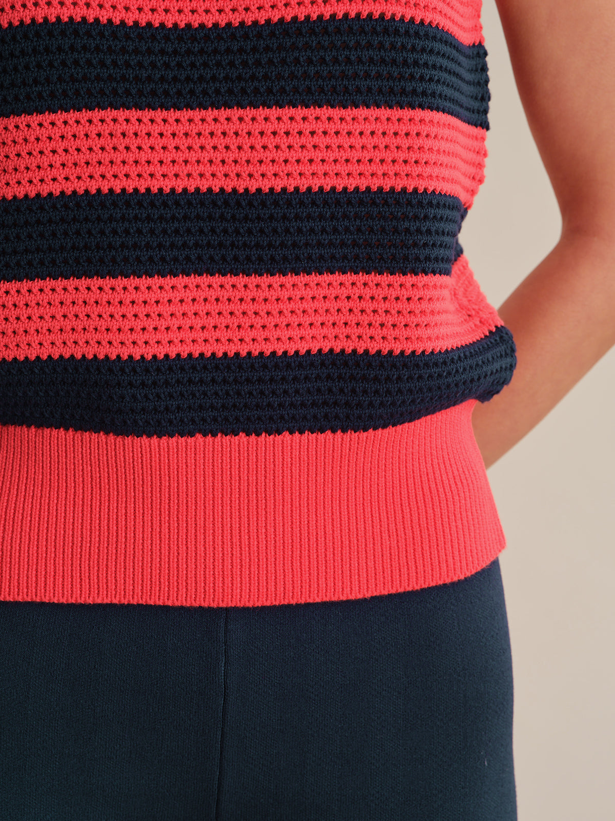 Red and black striped sleeveless top worn by a person on a neutral background